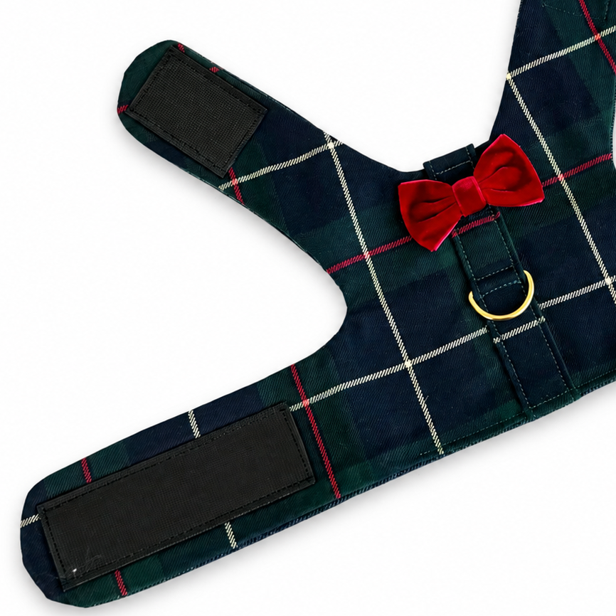 A dog harness in a navy blue tartan plaid pattern with thin red and white lines, featuring a red bow tie detail and a gold metal ring.
