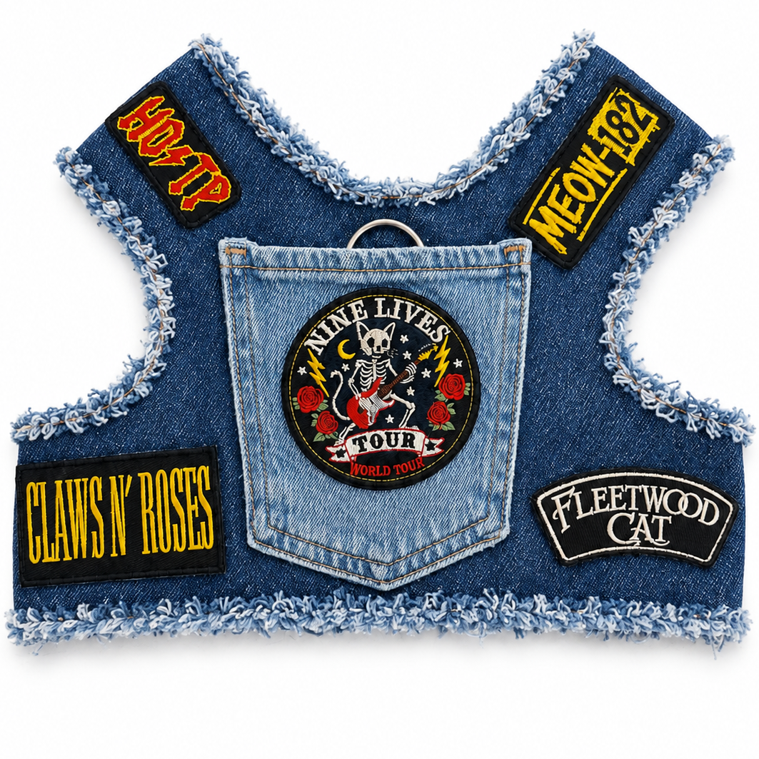 A denim vest accessory with a frayed edge, featuring multiple rock-themed patches including 'Claws 'N' Roses', 'Nine Lives Tour', 'Meow-182', 'Fleetwood Cat'