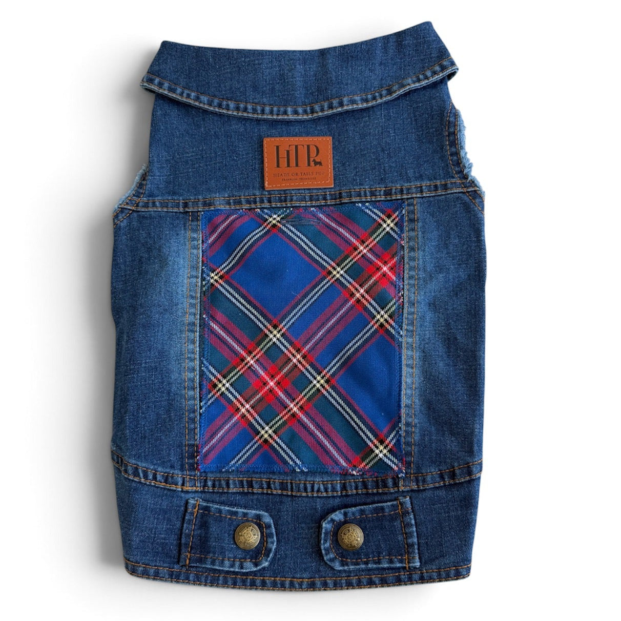 A small blue denim pet vest with a red, blue, and yellow plaid patterned patch pocket, featuring two brass snap buttons on the front, shown against a plain white background.