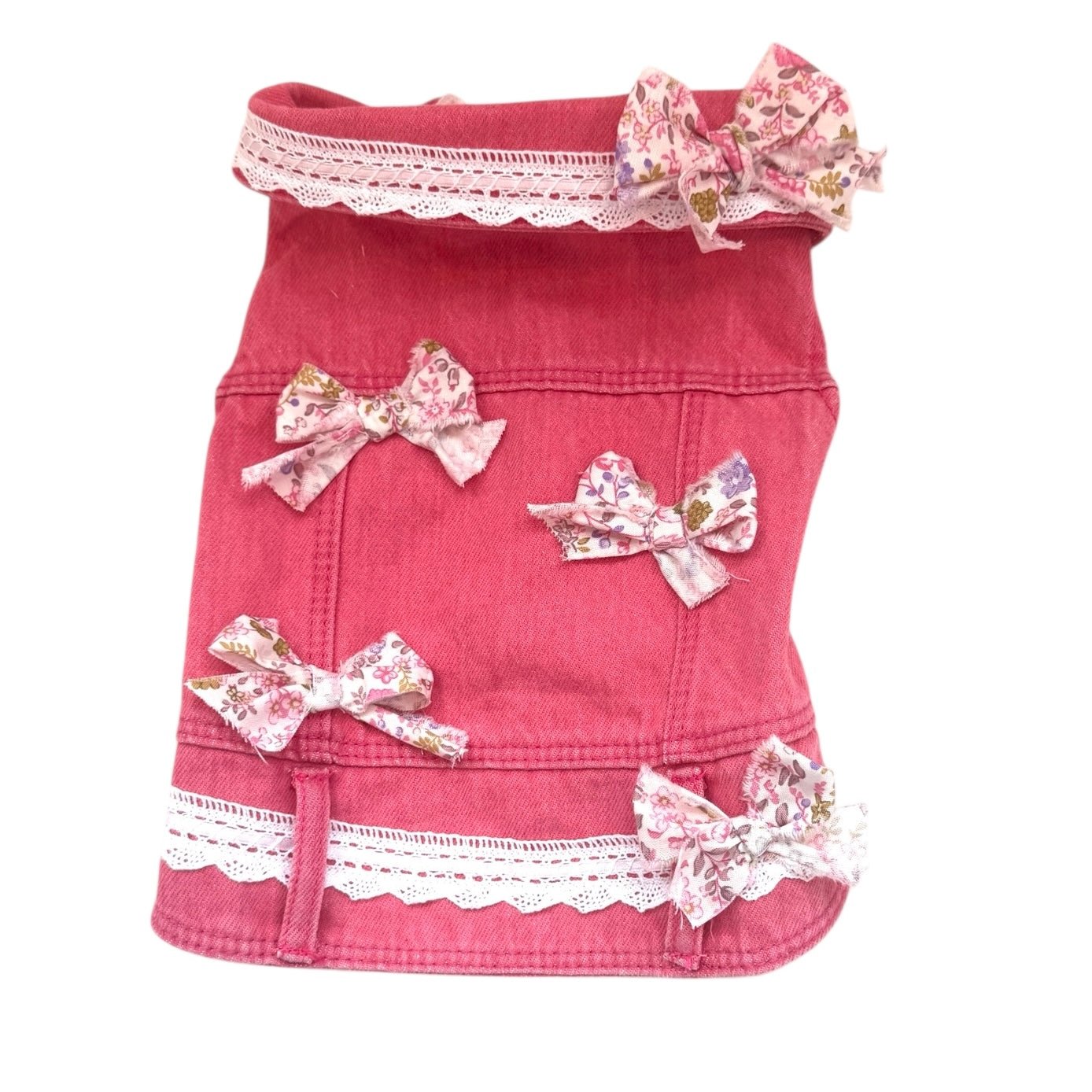 Pink dog vest with floral bows and lace details on a white background