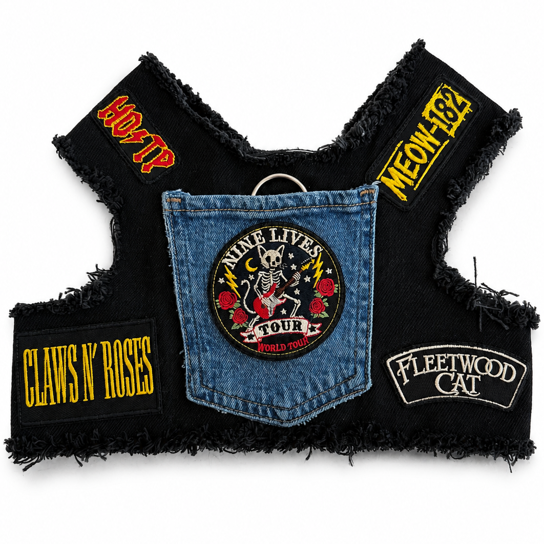 A black frayed biker harness featuring multiple band and rock-themed patches with Cat puns including Fleetwood Cat, Nine Lives Tour, Claws 'N' Roses, and Meow 182, arranged flat against a white background.