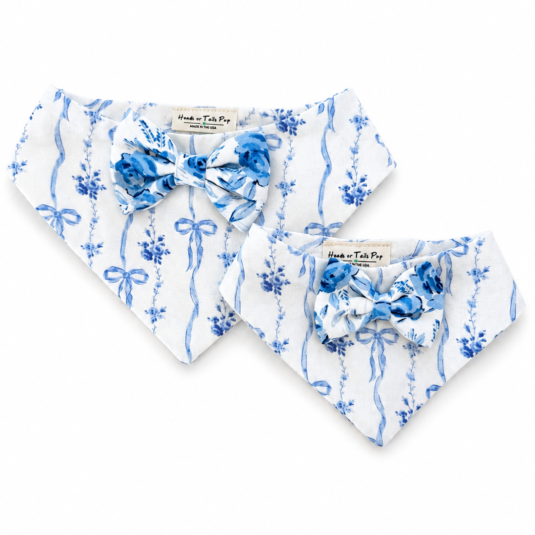 Two white pet bandanas with blue floral and ribbon patterns, each styled with a matching blue bow tie, displayed on a clean white background.