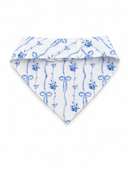 A white triangular pet bandana featuring a blue watercolor-style floral and ribbon pattern, displayed flat against a clean white background.