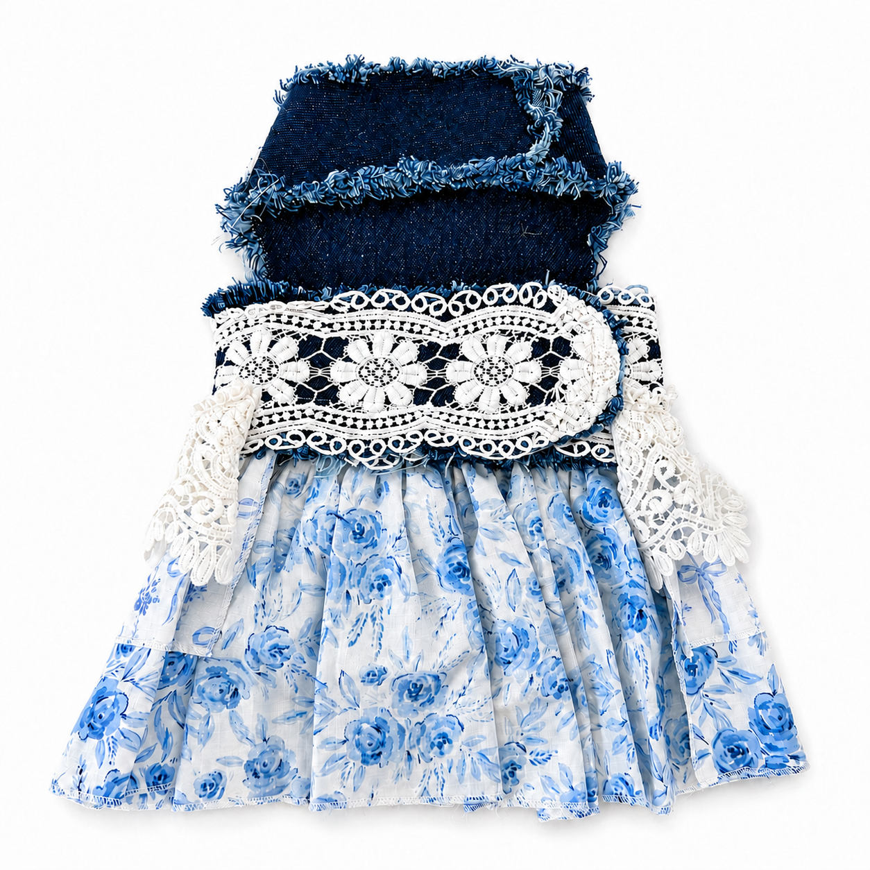 A sleeveless pet dress featuring a dark navy denim top with frayed trim, a white lace band with blue floral embroidery, and a tiered blue and white floral skirt, shown flat on a white background.