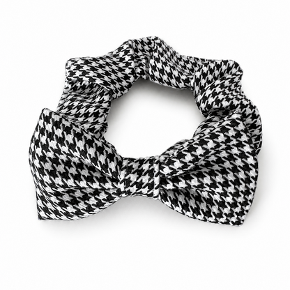 A black and white houndstooth patterned scrunchie collar with a large bow at the center, displayed on a clean white background.