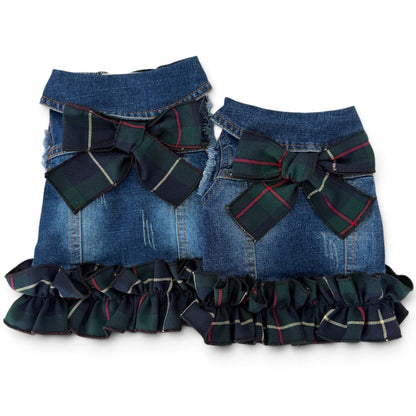 Two blue denim pet vests with a large green plaid bow at the center, and a matching ruffled trim along the bottom edge, shown against a plain white background.