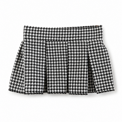A black and white houndstooth pleated mini skirt with a frayed edge, shown flat against a white background.
