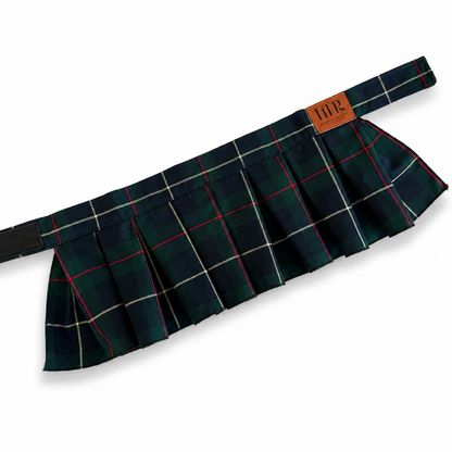 A pleated tartan skirt in a dark green and black plaid pattern with thin red and white stripes, featuring a brown leather brand patch that reads 'HTP'.