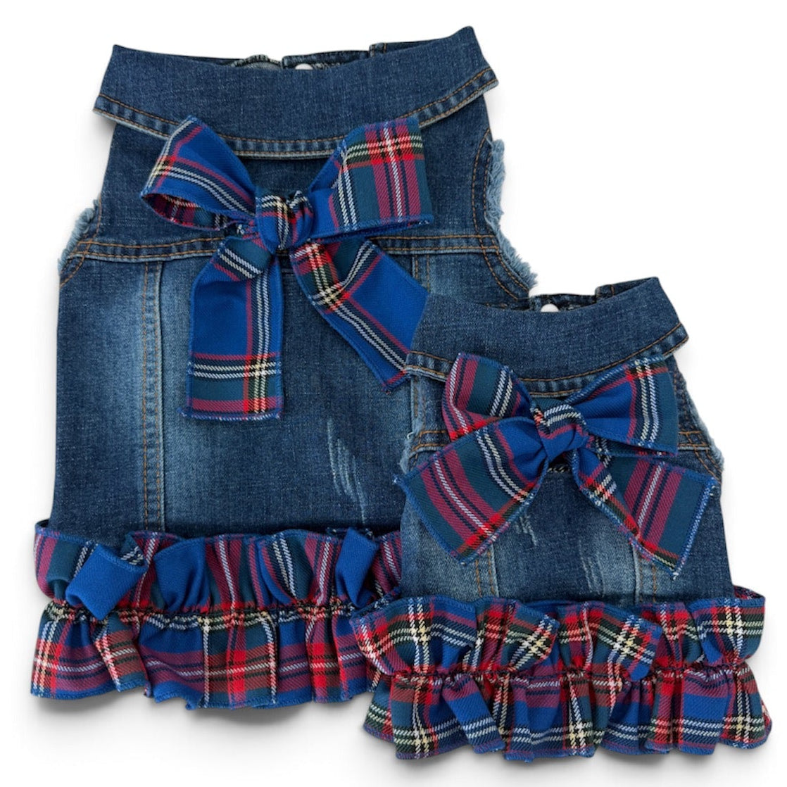 Two blue denim pet vests with a large red and blue plaid bow at the center, and a matching ruffled trim along the bottom edge, shown against a plain white background.